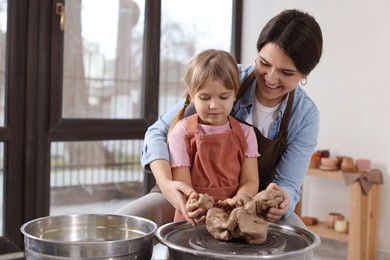 Photo of Hobby and craft. Smiling mother with her daughter making pottery indoors