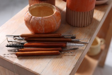 Photo of Set of different crafting tools and pottery on wooden shelf indoors, closeup