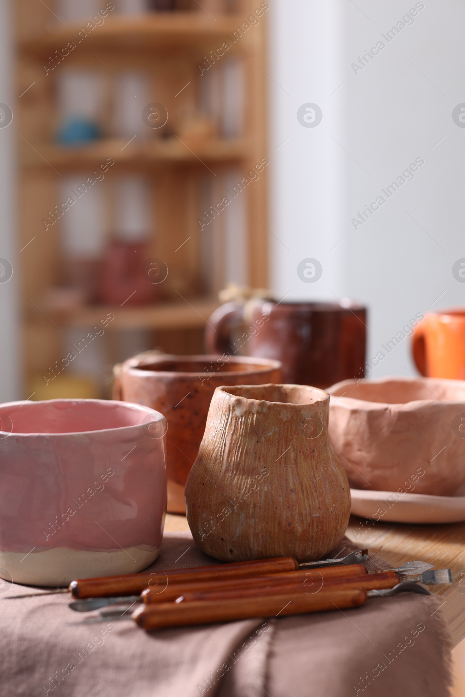 Photo of Set of different crafting tools and pottery on shelf indoors