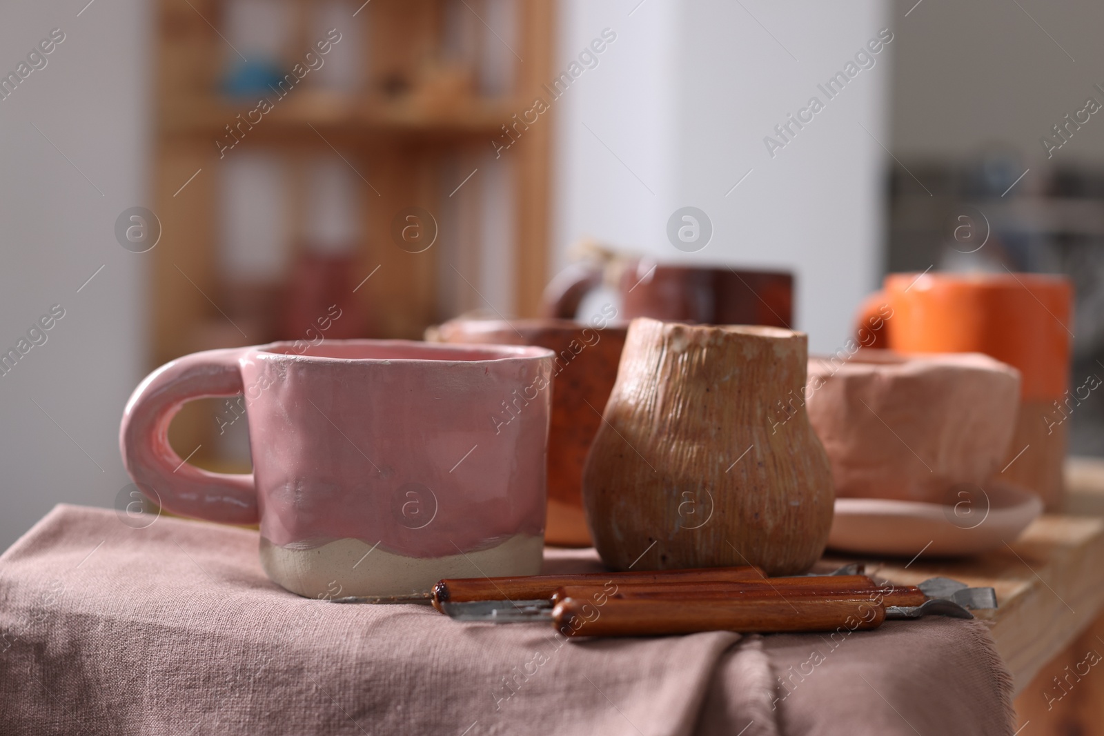 Photo of Set of different crafting tools and pottery on shelf indoors, closeup