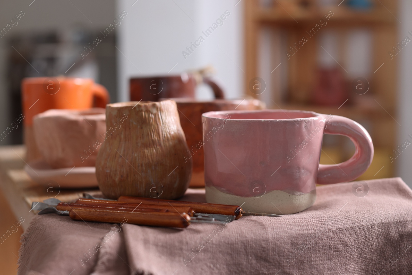 Photo of Set of different crafting tools and pottery on shelf indoors, closeup