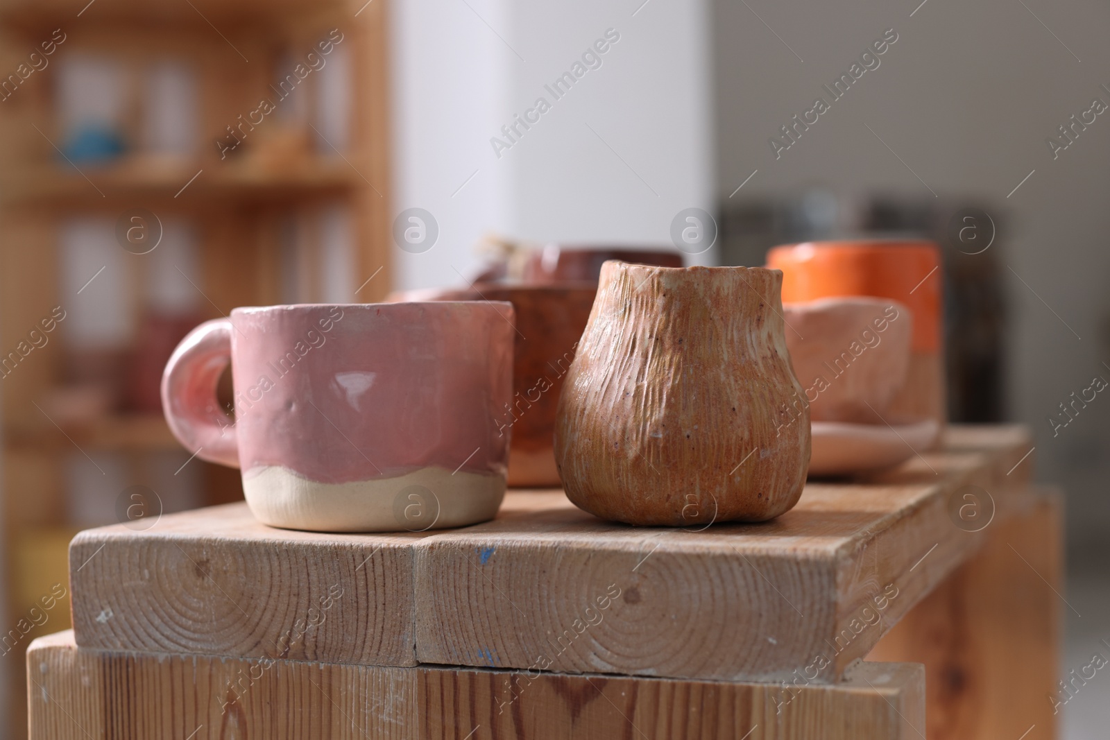 Photo of Beautiful pottery on wooden shelf indoors, closeup