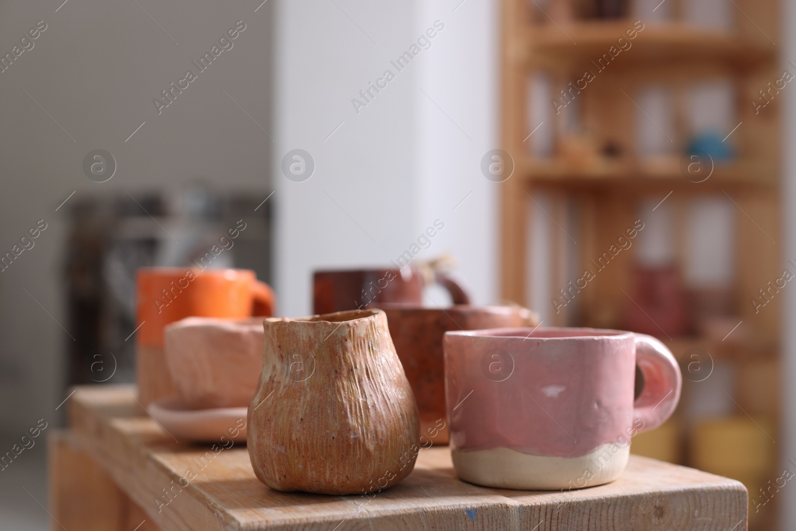 Photo of Beautiful pottery on wooden shelf indoors, closeup