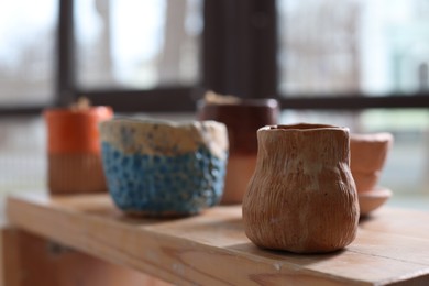 Photo of Beautiful pottery on wooden shelf indoors, closeup