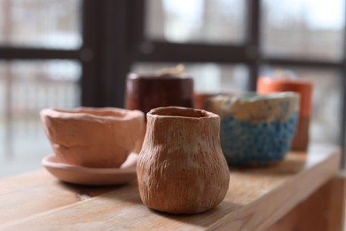 Photo of Beautiful pottery on wooden shelf indoors, closeup