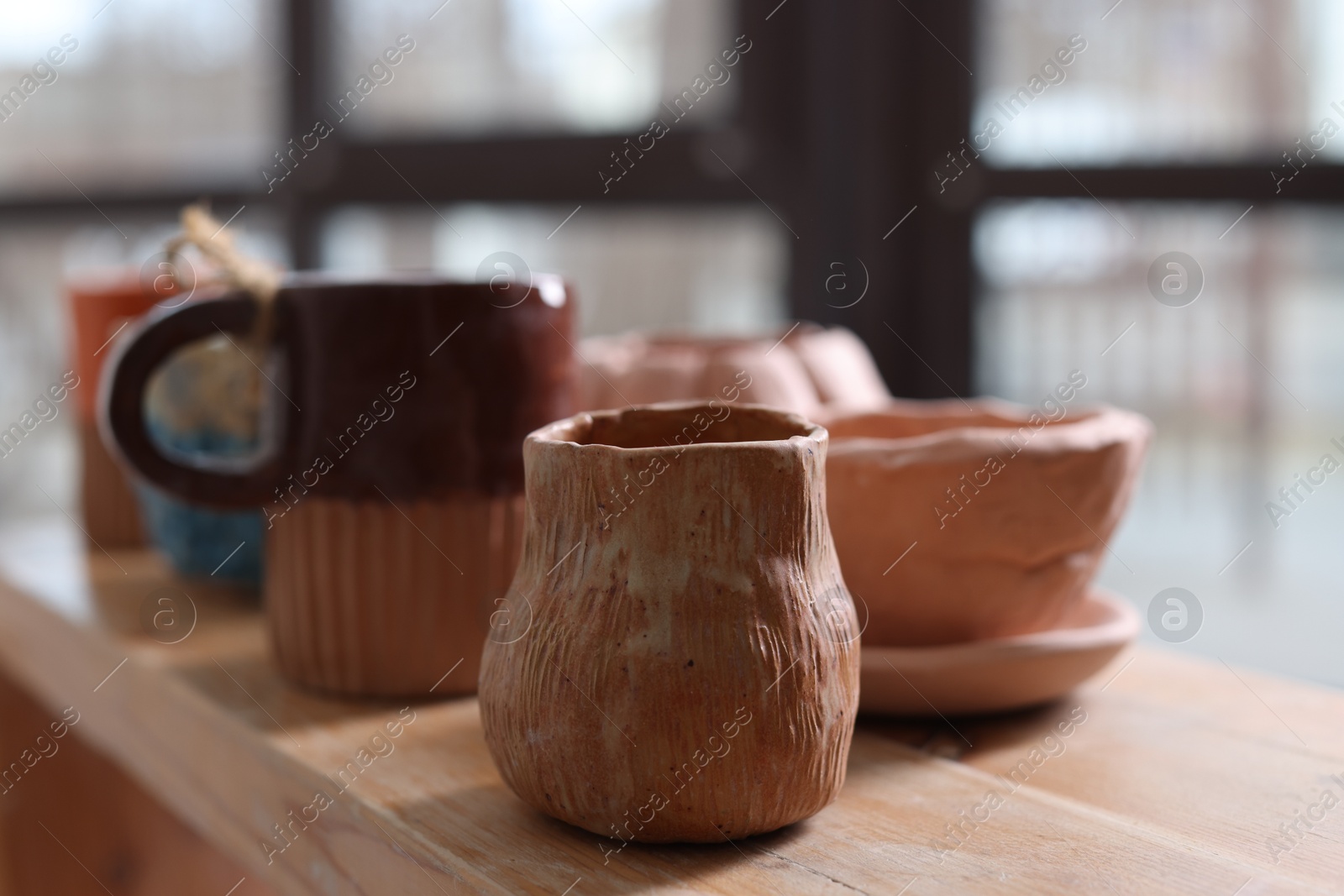 Photo of Beautiful pottery on wooden shelf indoors, closeup