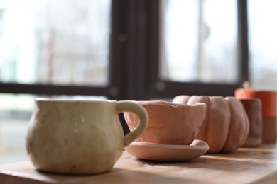 Photo of Beautiful pottery on wooden shelf indoors, closeup