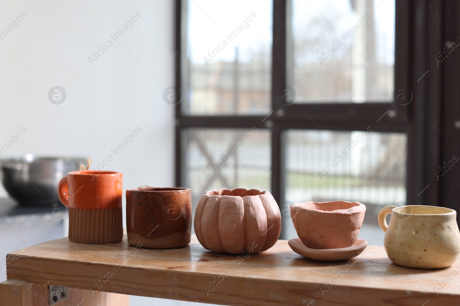 Photo of Beautiful pottery on wooden shelf indoors. Space for text