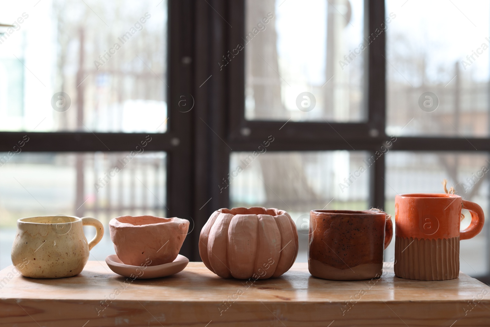 Photo of Beautiful pottery on wooden shelf indoors. Space for text