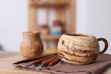 Photo of Set of different crafting tools and ceramic cup on wooden table indoors, closeup. Space for text