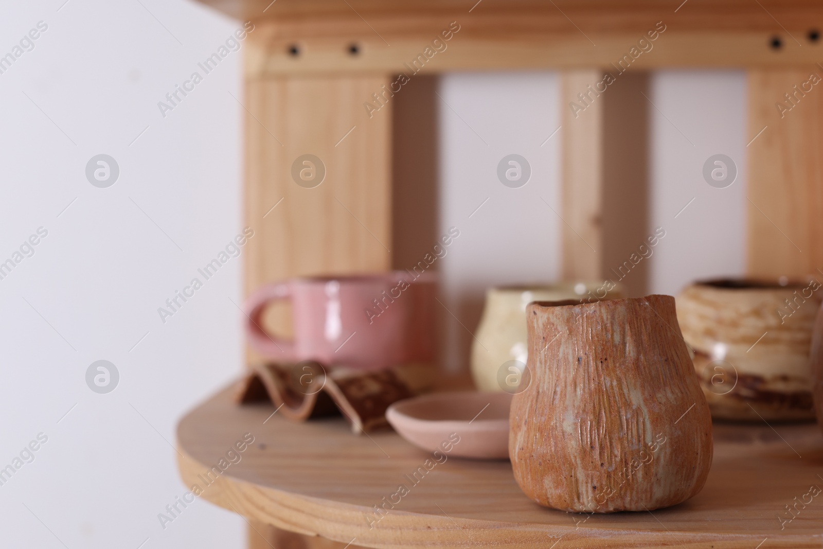 Photo of Beautiful pottery on wooden shelf indoors. Space for text