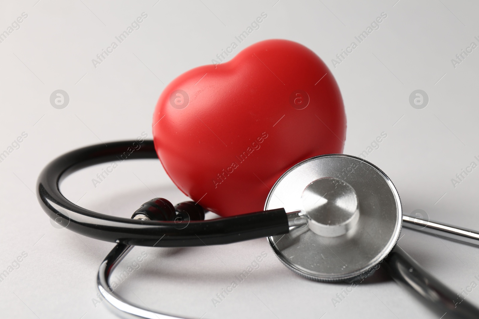 Photo of Cardiology. Stethoscope and red decorative heart on light gray background, closeup