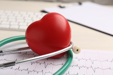 Photo of Cardiology. Stethoscope, cardiogram and red decorative heart on light table, closeup