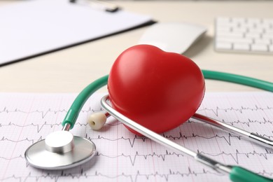 Photo of Cardiology. Stethoscope, cardiogram and red decorative heart on light table, closeup