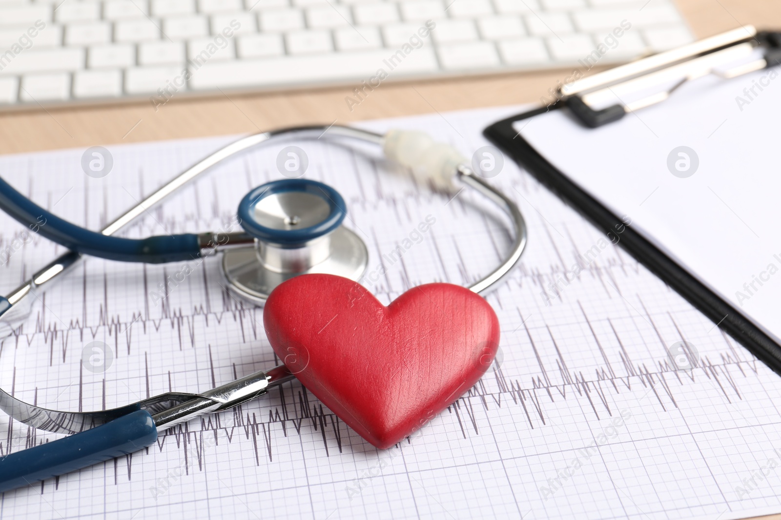 Photo of Cardiology. Cardiogram, clipboard, stethoscope, keyboard and red decorative heart on table, closeup