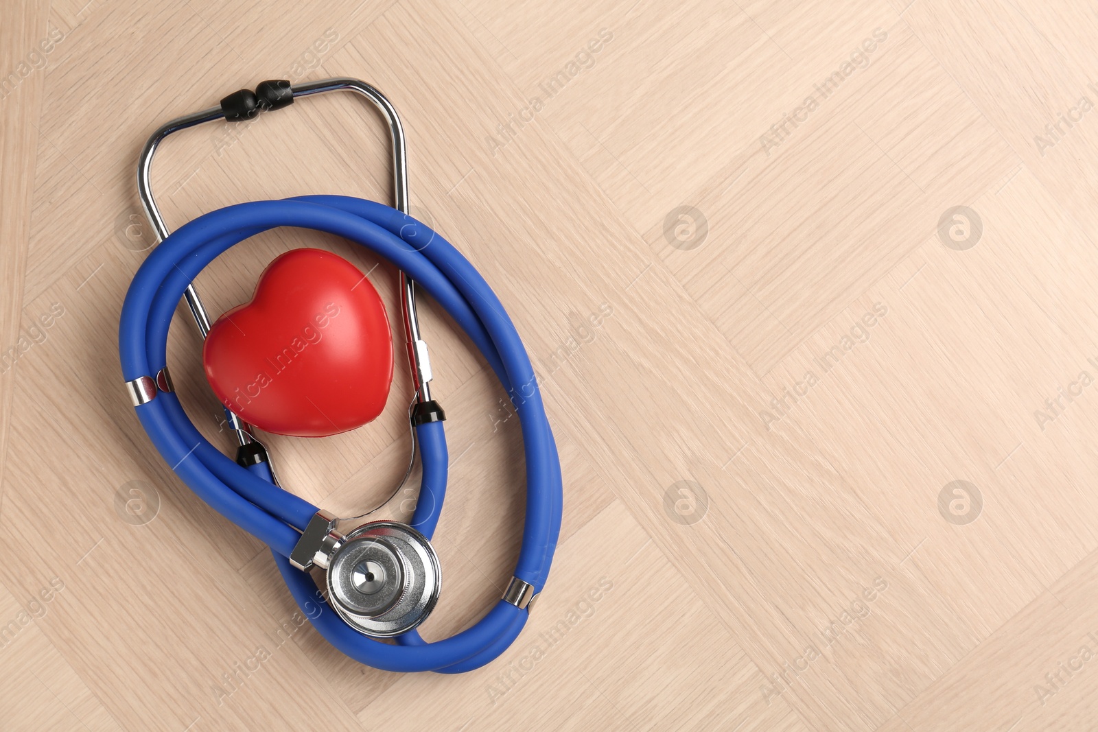 Photo of Cardiology. Stethoscope and red decorative heart on wooden table, top view. Space for text