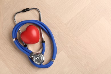 Photo of Cardiology. Stethoscope and red decorative heart on wooden table, top view. Space for text