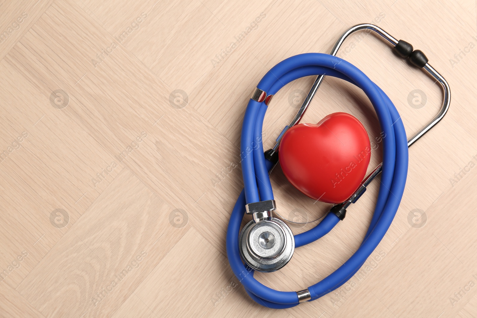 Photo of Cardiology. Stethoscope and red decorative heart on wooden table, top view. Space for text