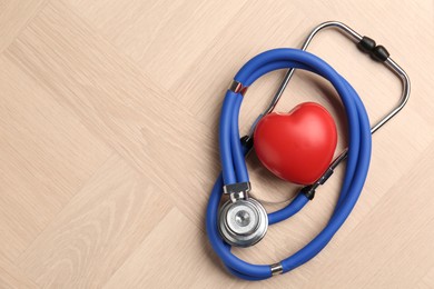 Photo of Cardiology. Stethoscope and red decorative heart on wooden table, top view. Space for text