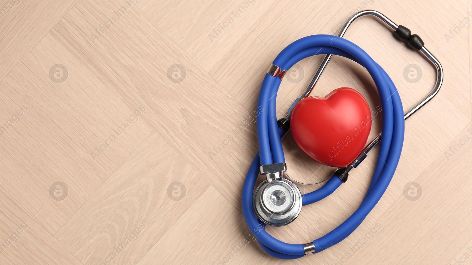 Photo of Cardiology. Stethoscope and red decorative heart on wooden table, top view. Space for text