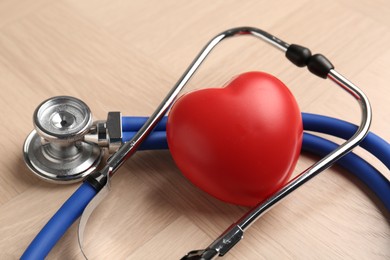 Photo of Cardiology. Stethoscope and red decorative heart on wooden table, closeup