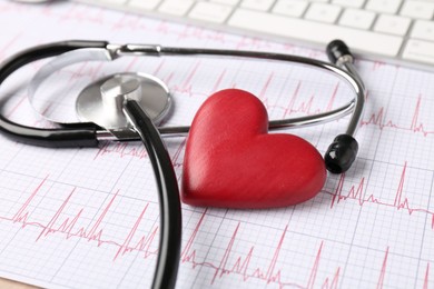 Photo of Cardiology. Stethoscope and red decorative heart on paper with cardiogram, closeup