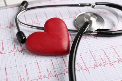 Photo of Cardiology. Stethoscope and red decorative heart on paper with cardiogram, closeup