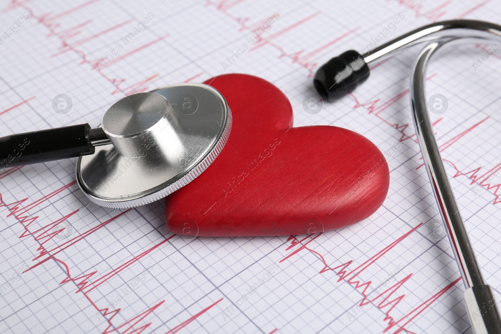 Photo of Cardiology. Stethoscope and red decorative heart on paper with cardiogram, closeup