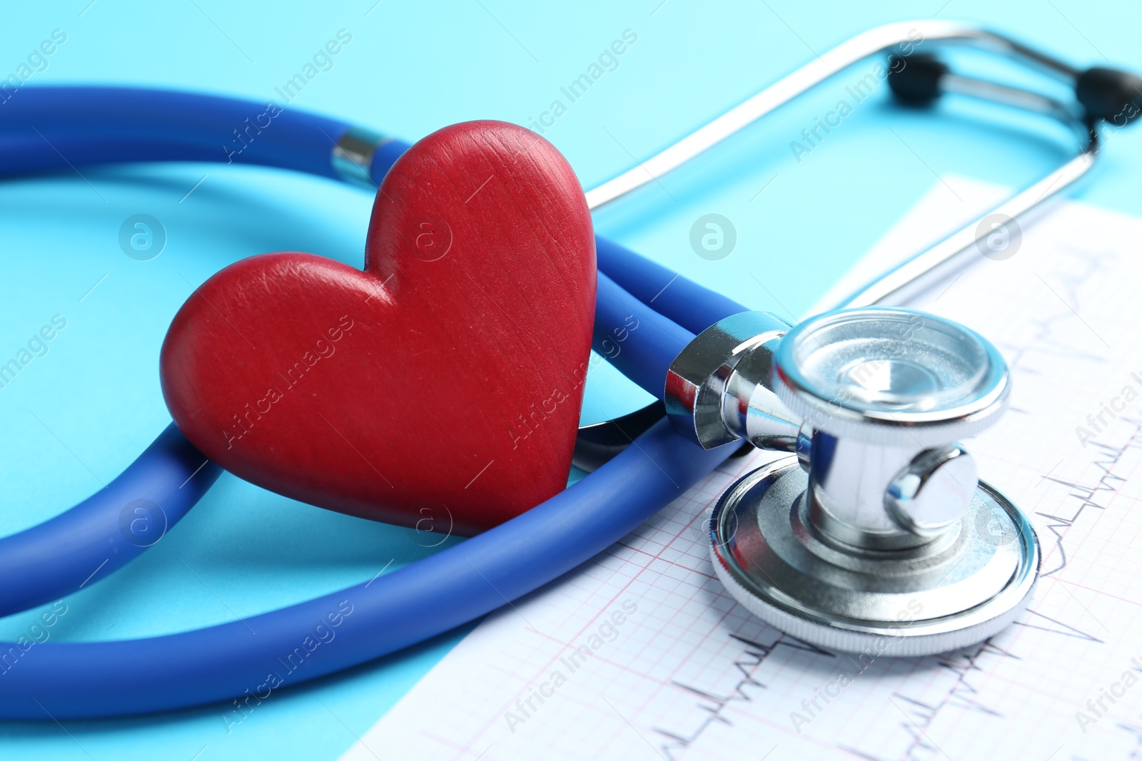 Photo of Cardiology. Stethoscope, red decorative heart and cardiogram on light blue background, closeup