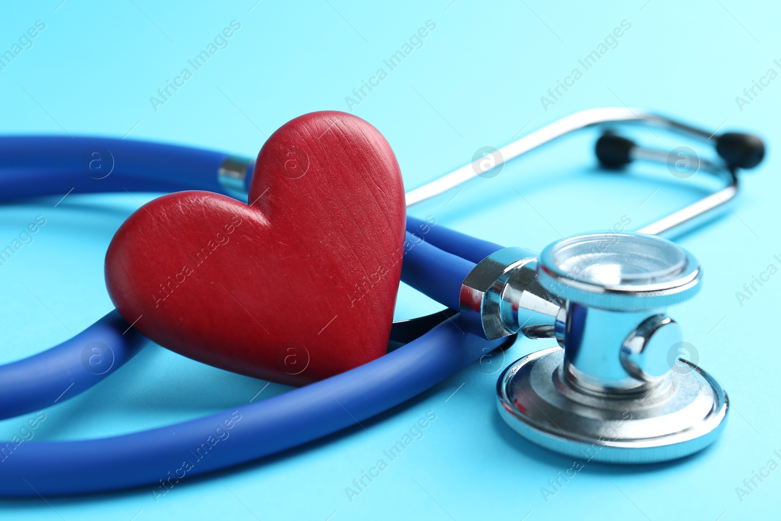 Photo of Cardiology. Stethoscope and red decorative heart on light blue background, closeup