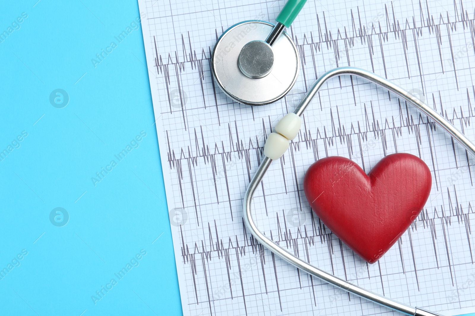 Photo of Cardiology. Stethoscope, red decorative heart and cardiogram on light blue background, flat lay. Space for text