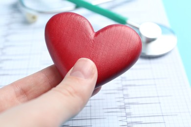 Photo of Cardiology. Woman with red decorative heart on blurred background, closeup