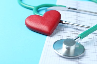 Photo of Cardiology. Stethoscope, red decorative heart and cardiogram on light blue background, closeup. Space for text