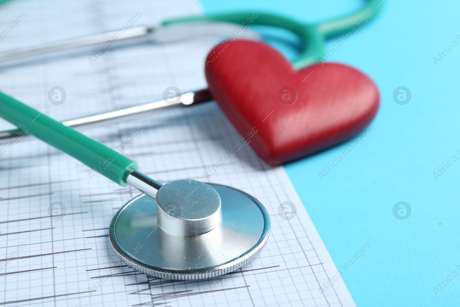 Photo of Cardiology. Stethoscope, red decorative heart and cardiogram on light blue background, closeup