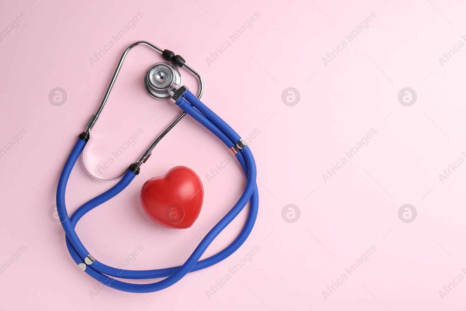 Photo of Cardiology. Stethoscope and red decorative heart on pale pink background, flat lay. Space for text