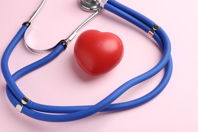 Photo of Cardiology. Stethoscope and red decorative heart on pale pink background, closeup