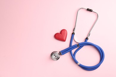 Photo of Cardiology. Stethoscope and red decorative heart on pale pink background, flat lay. Space for text