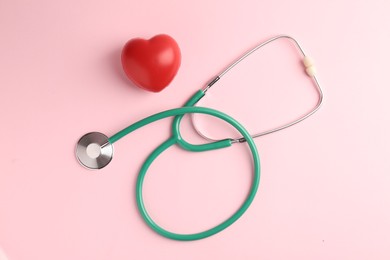 Photo of Cardiology. Stethoscope and red decorative heart on pale pink background, flat lay