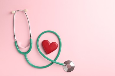 Photo of Cardiology. Stethoscope and red decorative heart on pale pink background, flat lay. Space for text