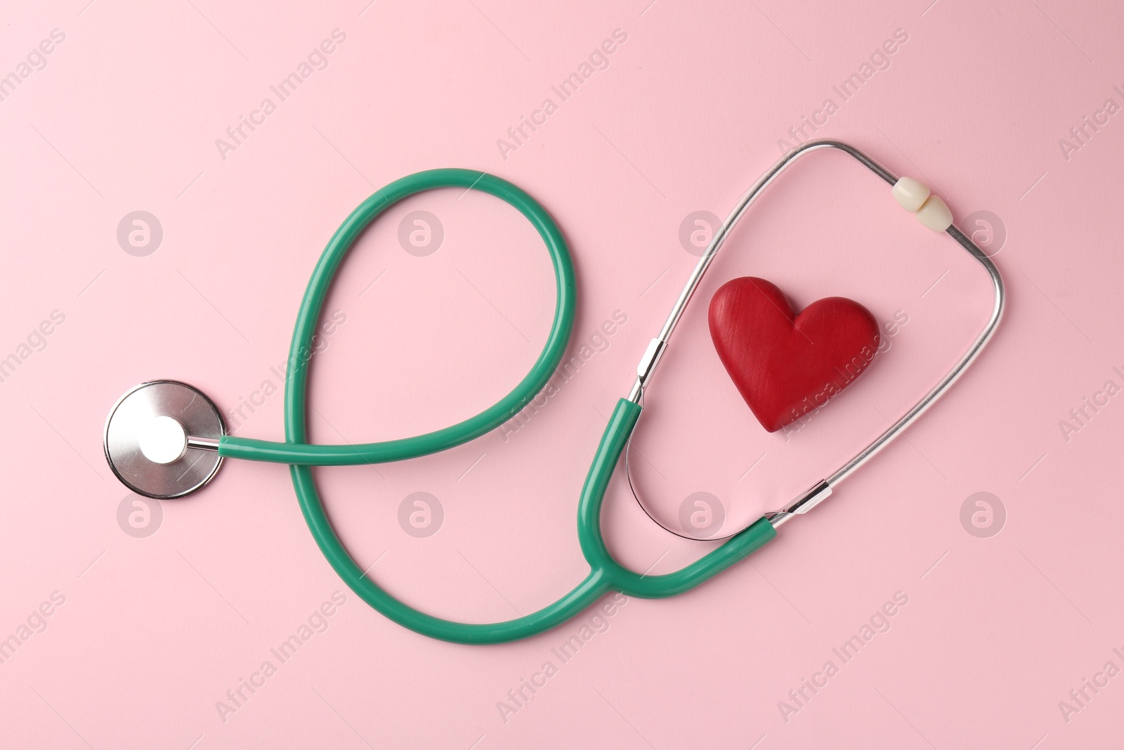 Photo of Cardiology. Stethoscope and red decorative heart on pale pink background, flat lay