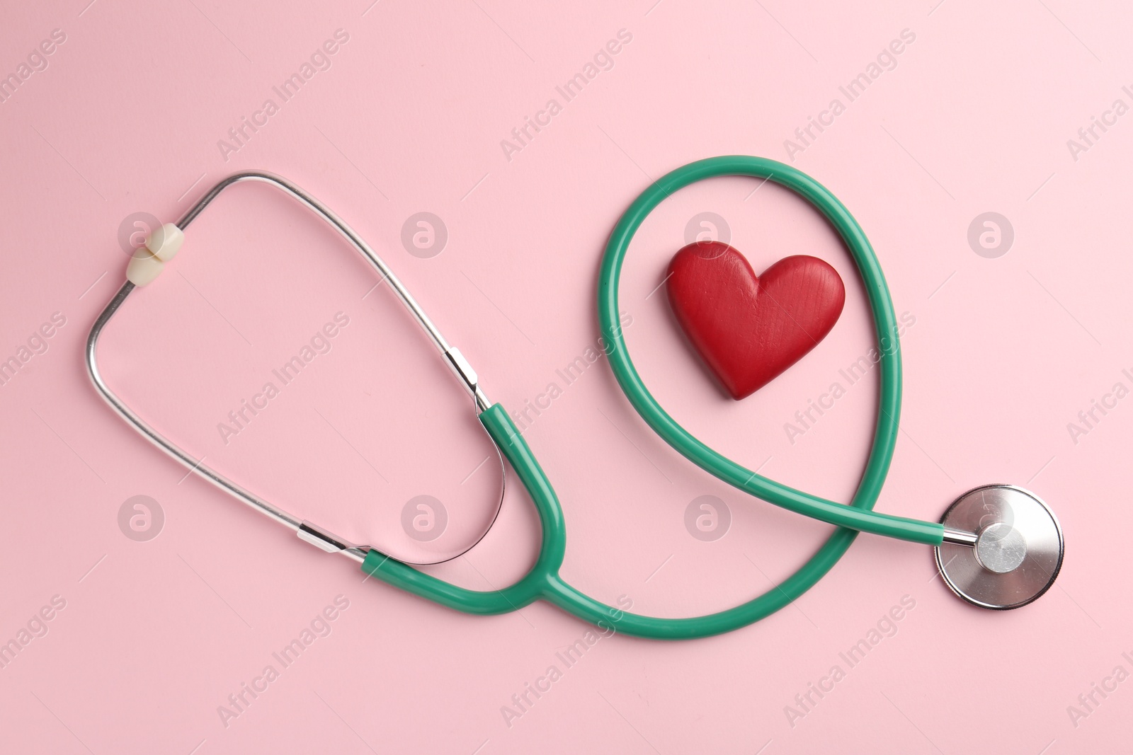 Photo of Cardiology. Stethoscope and red decorative heart on pale pink background, flat lay