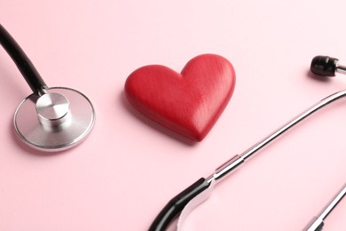 Photo of Cardiology. Stethoscope and red decorative heart on pale pink background, closeup