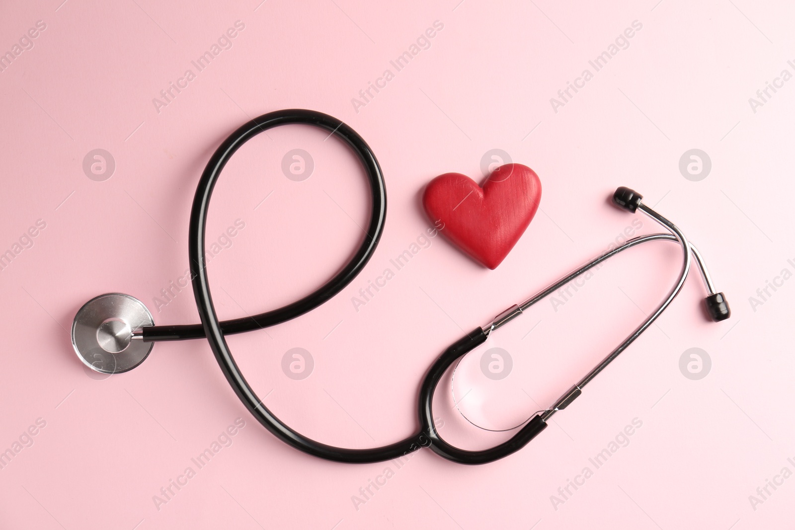 Photo of Cardiology. Stethoscope and red decorative heart on pale pink background, flat lay