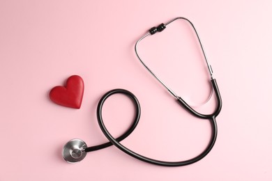 Photo of Cardiology. Stethoscope and red decorative heart on pale pink background, flat lay