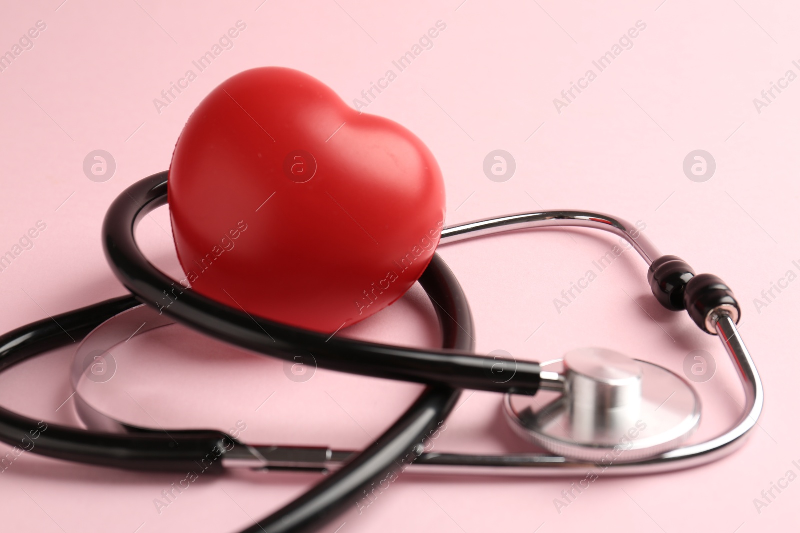 Photo of Cardiology. Stethoscope and red decorative heart on pale pink background, closeup