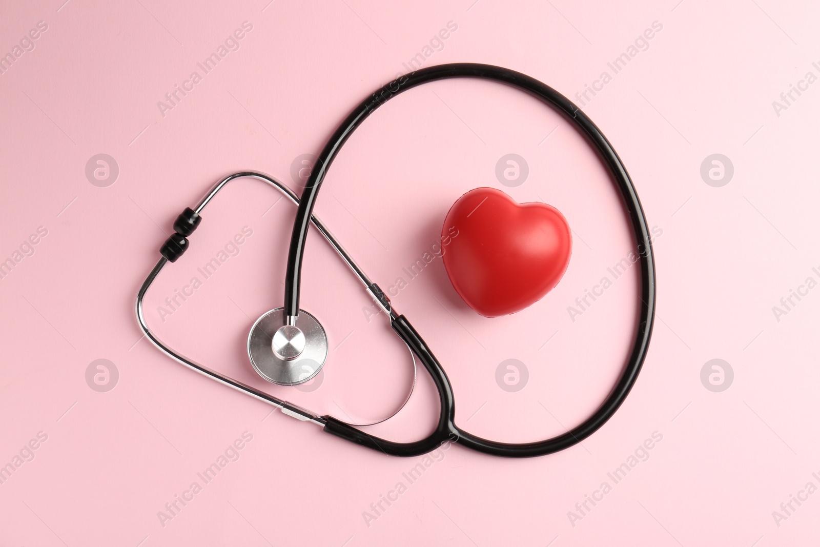 Photo of Cardiology. Stethoscope and red decorative heart on pale pink background, flat lay