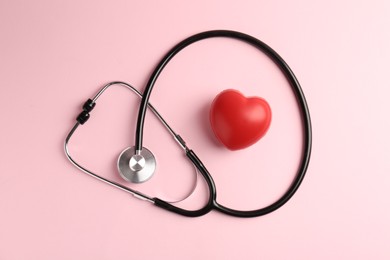 Photo of Cardiology. Stethoscope and red decorative heart on pale pink background, flat lay