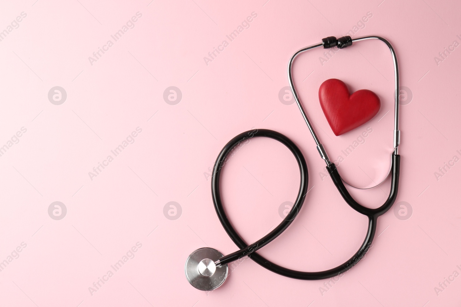 Photo of Cardiology. Stethoscope and red decorative heart on pale pink background, flat lay. Space for text