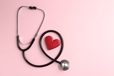 Photo of Cardiology. Stethoscope and red decorative heart on pale pink background, flat lay. Space for text