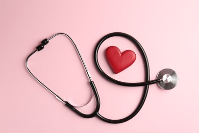 Photo of Cardiology. Stethoscope and red decorative heart on pale pink background, flat lay